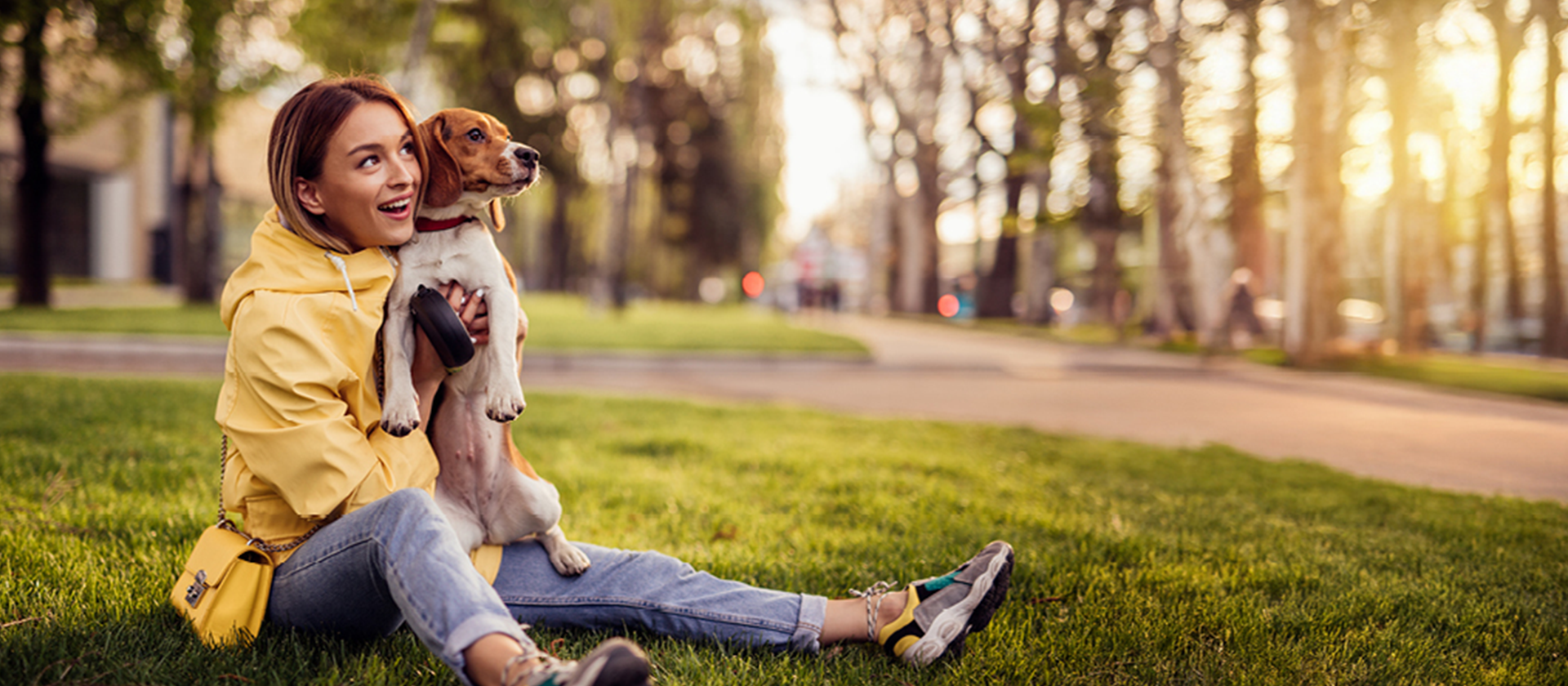 Eine Frau hält einen Hund im Gras und genießt die Zeit im Freien.