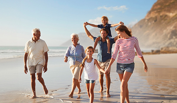 Eine Familie spaziert am Strand, umarmt sich und genießt die gemeinsame Zeit in der Sonne.