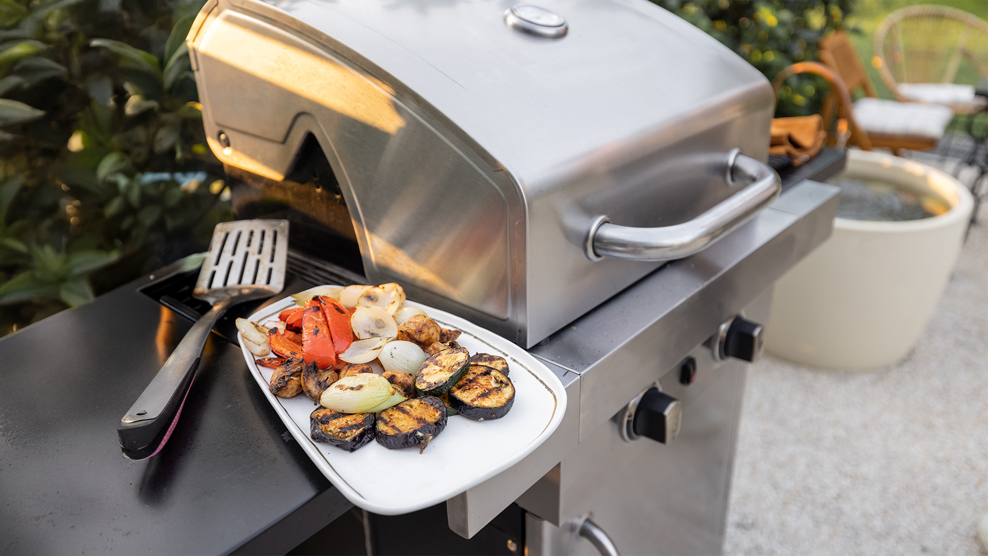 Bild eines Gasgrills auf dem ein Teller mit Grillsgemüse steht.