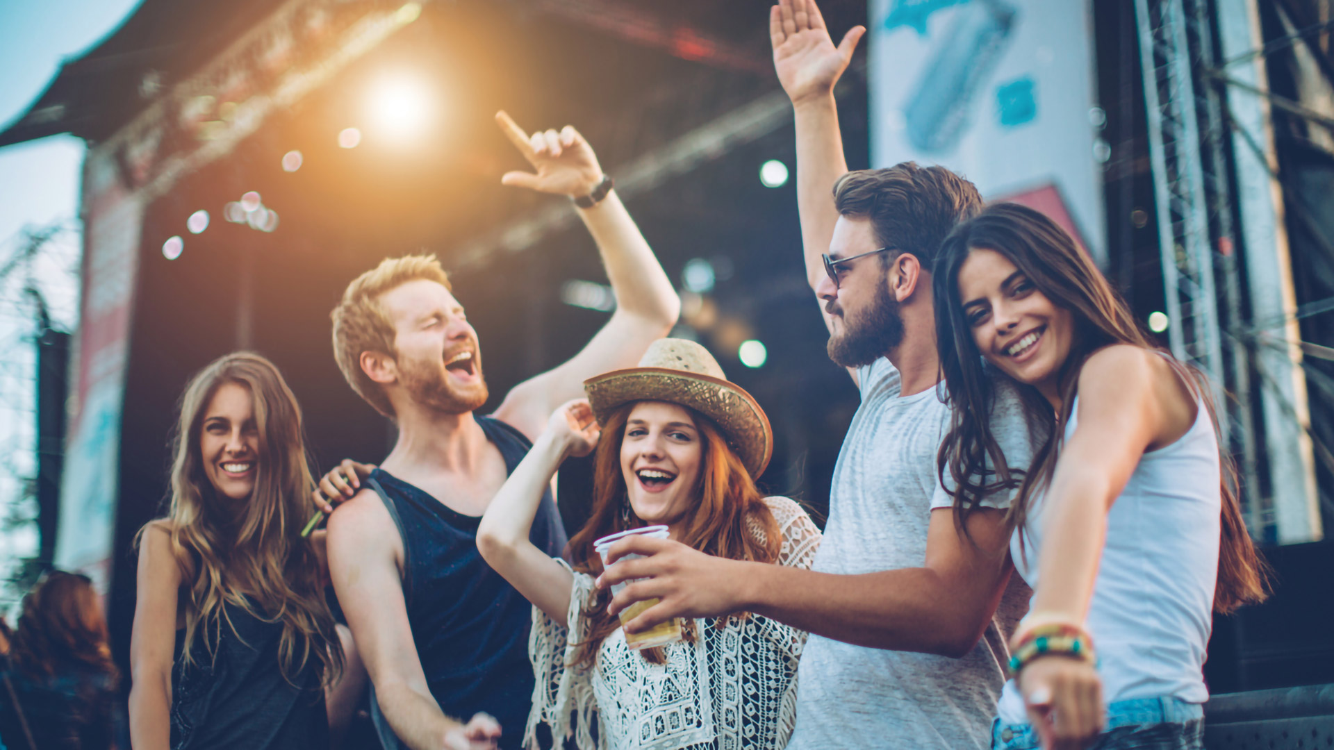 Eine Gruppe junger Menschen genießt die Atmosphäre eines Musikfestivals und tanzt zur Musik.