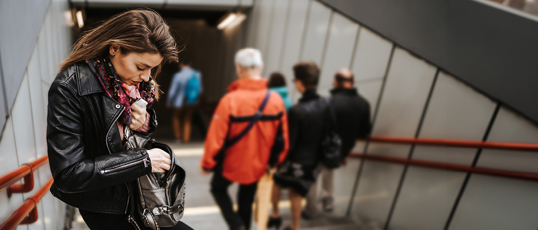 Ein Foto zeigt eine Frau, die in einer U-Bahn-Passage in die Tasche greift.