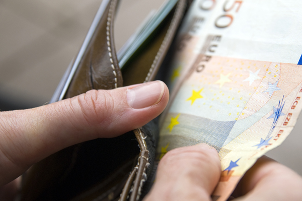 Eine Hand zieht einen Zwanzig-Euro-Schein aus einer braunen Ledergeldbörse